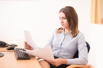 Cute woman reading a document in the office