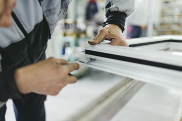 Naklejka premium Manual worker assembling PVC doors and windows. Manufacturing jobs. Selective focus. Factory for aluminum and PVC windows and doors production.