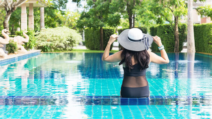 Fototapeta na wymiar Women lifestyle relaxing near luxury swimming pool sunbath, summer day at the beach resort in the hotel. Summer Concept.