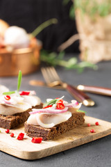 Sandwich with herring, black bread, black background, hot pepper, pickled onion, vertical, selective focus