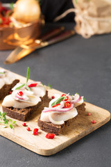 Sandwich with herring, black bread, black background, hot pepper, pickled onion, vertical, selective focus