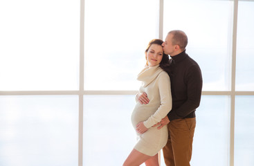 Pregnant woman and husband are smiling spending time together at home men touching tommy