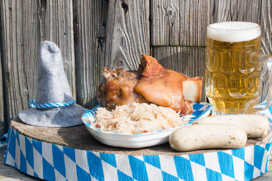 Haxe mit Sauerkraut,Weisswurst und Bier traditionell f&uuml;r das Oktoberfest rustikal vor Holzhintergrund