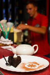 a piece of cake on a plate with tea is on the bar