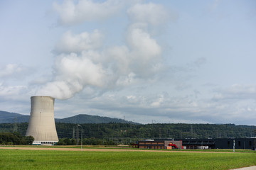 Fototapeta na wymiar nuclear power plant chimney with landscape mountain meadow green fielw and sky
