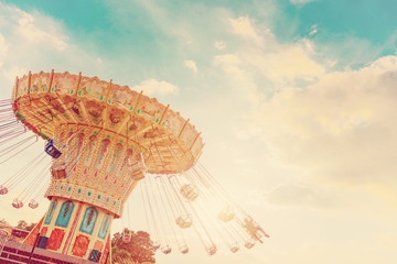 carousel ride spins fast in the air at sunset - vintage filter effects - a swinging carousel fair ride at dusk - obrazy, fototapety, plakaty