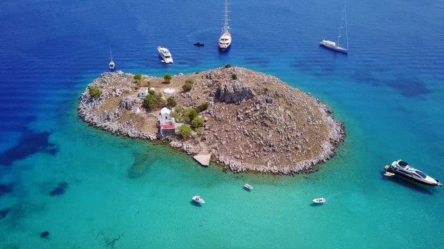 August 2017: Aerial drone video of small heart shaped island with picturesque church of Agia Marina and turquoise clear waters, Symi island, Dodecanese, Aegean, Greece