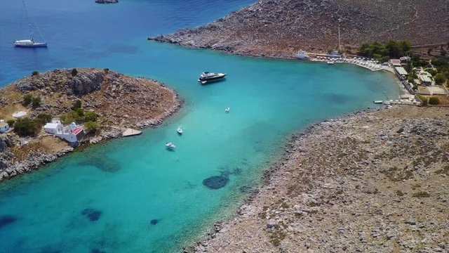 August 2017: Aerial drone video of small heart shaped island with picturesque church of Agia Marina and turquoise clear waters, Symi island, Dodecanese, Aegean, Greece