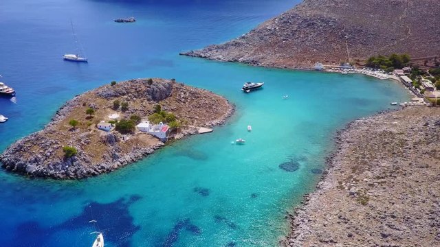 August 2017: Aerial drone video of small heart shaped island with picturesque church of Agia Marina and turquoise clear waters, Symi island, Dodecanese, Aegean, Greece