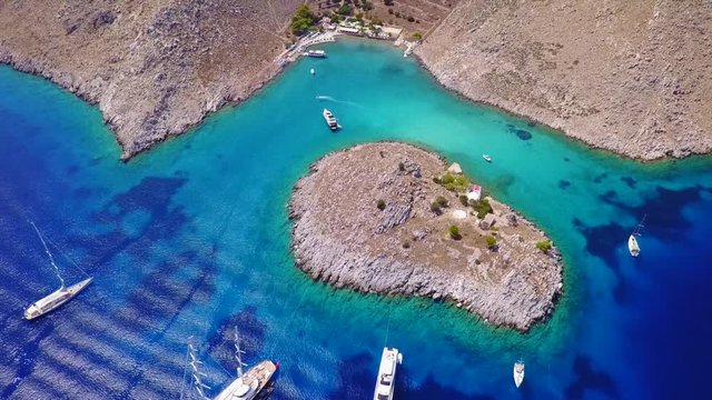 August 2017: Aerial drone video of small heart shaped island with picturesque church of Agia Marina and turquoise clear waters, Symi island, Dodecanese, Aegean, Greece
