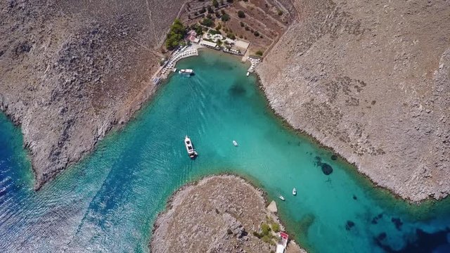 August 2017: Aerial drone video of small heart shaped island with picturesque church of Agia Marina and turquoise clear waters, Symi island, Dodecanese, Aegean, Greece