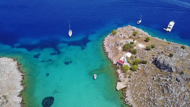 August 2017: Aerial drone video of small heart shaped island with picturesque church of Agia Marina and turquoise clear waters, Symi island, Dodecanese, Aegean, Greece
