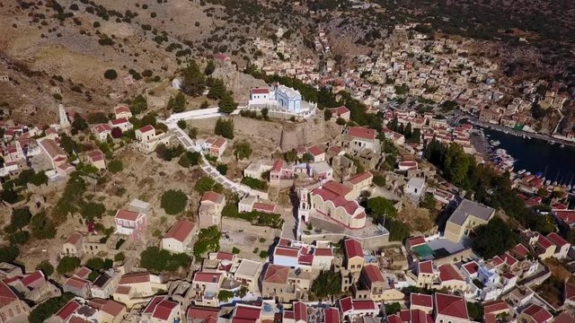 August 2017: Aerial drone video of picturesque castle in Ano chora in island of Symi with traditional architecture and dominant colors, Dodecanese, Aegean, Greece