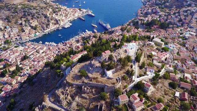 August 2017: Aerial drone video of picturesque castle in Ano chora in island of Symi with traditional architecture and dominant colors, Dodecanese, Aegean, Greece