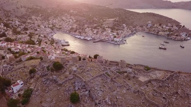August 2017: Aerial drone video of picturesque island and main port of Symi with traditional architecture and dominant colors at dusk, Dodecanese, Aegean, Greece