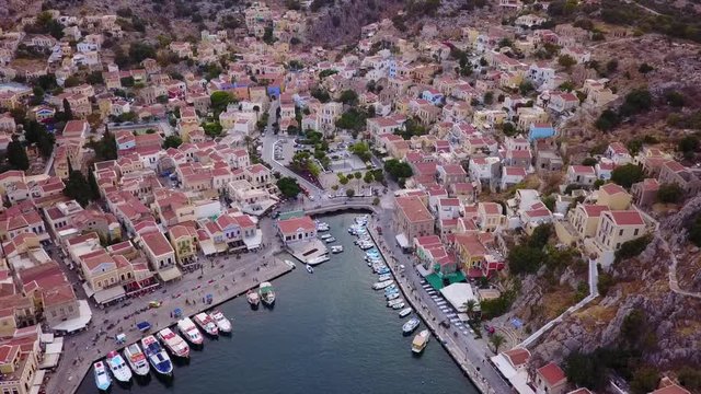 August 2017: Aerial drone video of picturesque island and main port of Symi with traditional architecture and dominant colors at dusk, Dodecanese, Aegean, Greece
