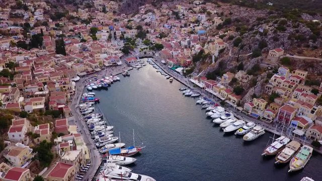 August 2017: Aerial drone video of picturesque island and main port of Symi with traditional architecture and dominant colors at dusk, Dodecanese, Aegean, Greece