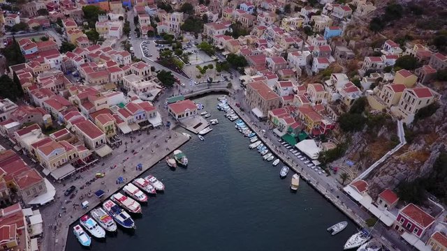 August 2017: Aerial drone video of picturesque island and main port of Symi with traditional architecture and dominant colors at dusk, Dodecanese, Aegean, Greece