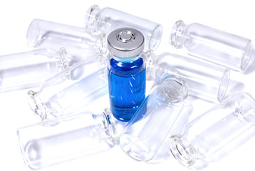 Flacon with blue vaccine and heap of empty bottles