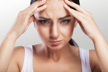 Young woman with headache, which holds her head, on a gray background, macrophotography, migraine, beautiful girl, professional makeup.