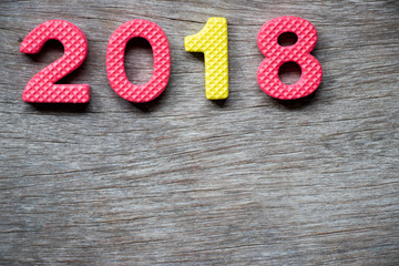 Toy foam alphabet in wording 2018 on wood plate background (Concept for Happy new year decoration)