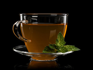 Fresh mint and tea in cup and saucer from glass