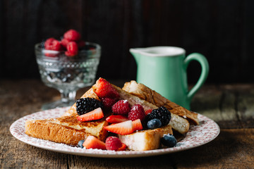 French toast served with syrup and fresh berries, horizontal with negative space