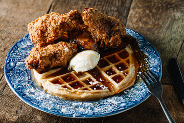 Chicken wings and waffles served with butter and blackberry syrup