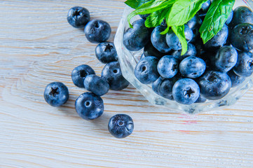 Blueberries with leaves in white wooden background.