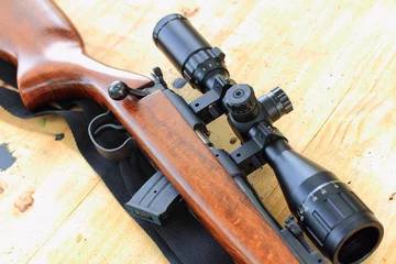 Foto op Canvas close-up van geweertelescoop voor sportjacht op houten tafel © toodtuphoto