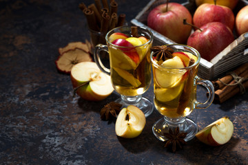 glasses of hot apple tea with spices on dark table