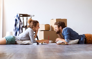 Young couple moving in new house, lying on the floor.