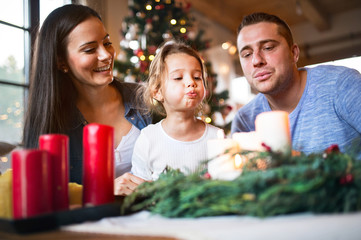 Young family blowing candles on advent wreath.