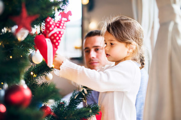 Young father with daugter decorating Christmas tree together.