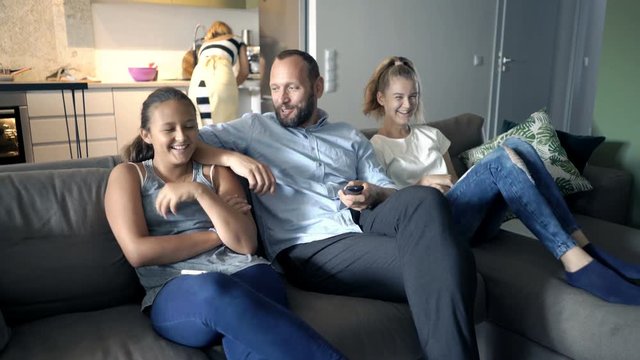 Happy family watching TV sitting on sofa at home
