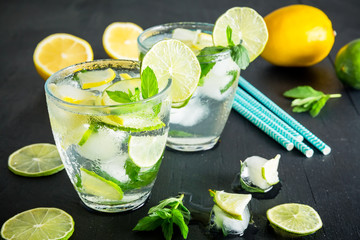 Refreshing fresh cocktail with crushed ice and lime with lemon on dark background