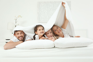 Family lying on bed in hotel room - obrazy, fototapety, plakaty