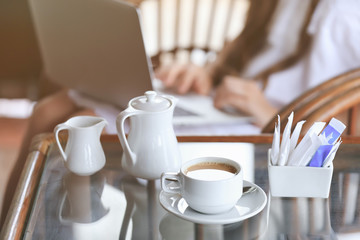 Cup of tasty hot coffee, sugar and milk jug on table in cafe