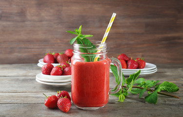 Mason jar with fresh strawberry smoothie on wooden table