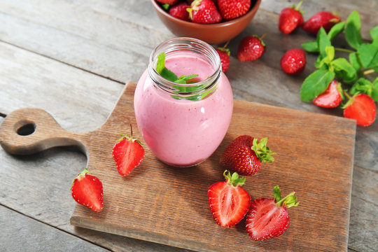 Jar with fresh strawberry smoothie on wooden table