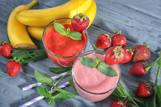 Glasses of fresh strawberry and banana smoothies on wooden table
