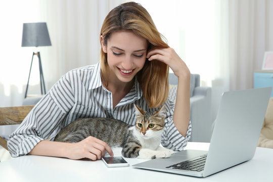 Young Beautiful Woman With Cat Using Laptop At Home