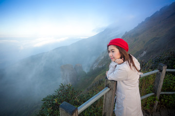 Young woman on a cliff overlooking the mountains
