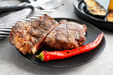 Cut steak with chili pepper on black plate