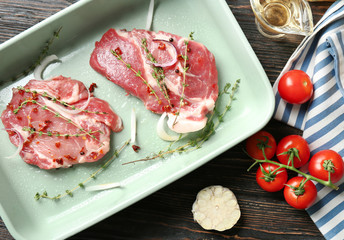 Baking dish with fresh raw steaks on table