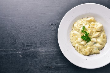 Dumpling from potatoes under cheese sauce. On a wooden background. Top view. Free space.