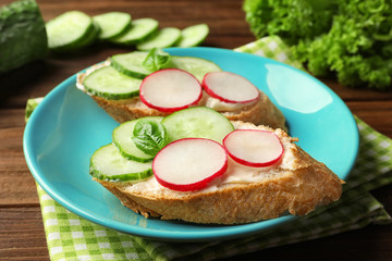 Plate of tasty sandwiches with fresh cucumber on table