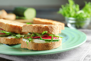 Plate of tasty sandwiches with fresh cucumber on table