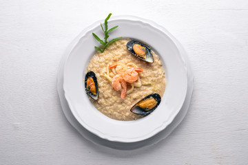 Risotto with seafood, shrimp, mussels and squids and cheese. On a wooden background. Top view. Free space.