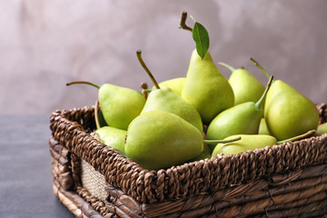 Wicker basket with delicious ripe pears on table